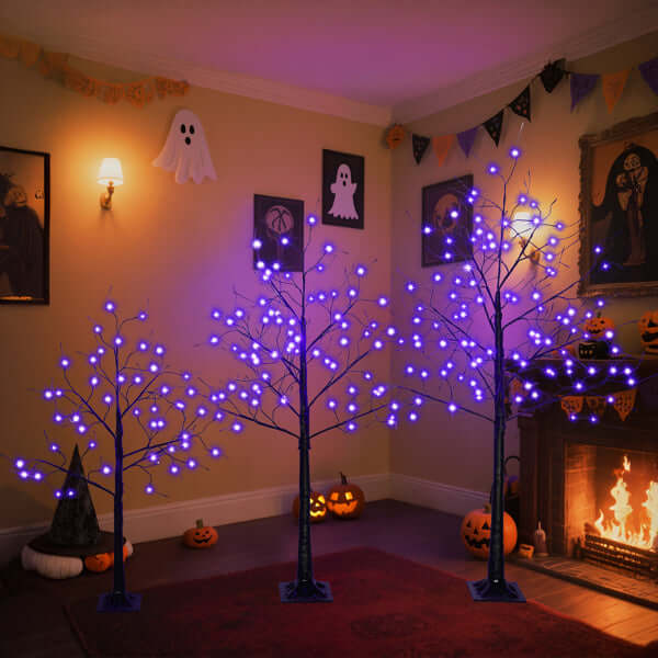 Halloween ghost trees with lights in a spooky decorated room with glowing purple lights and Halloween decor.